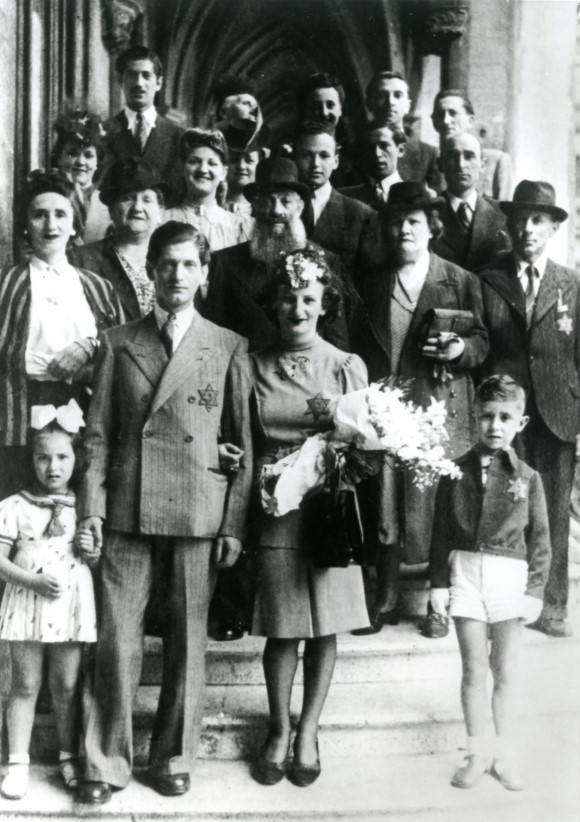 A black and white photograph of a wedding party standing on the steps of a building