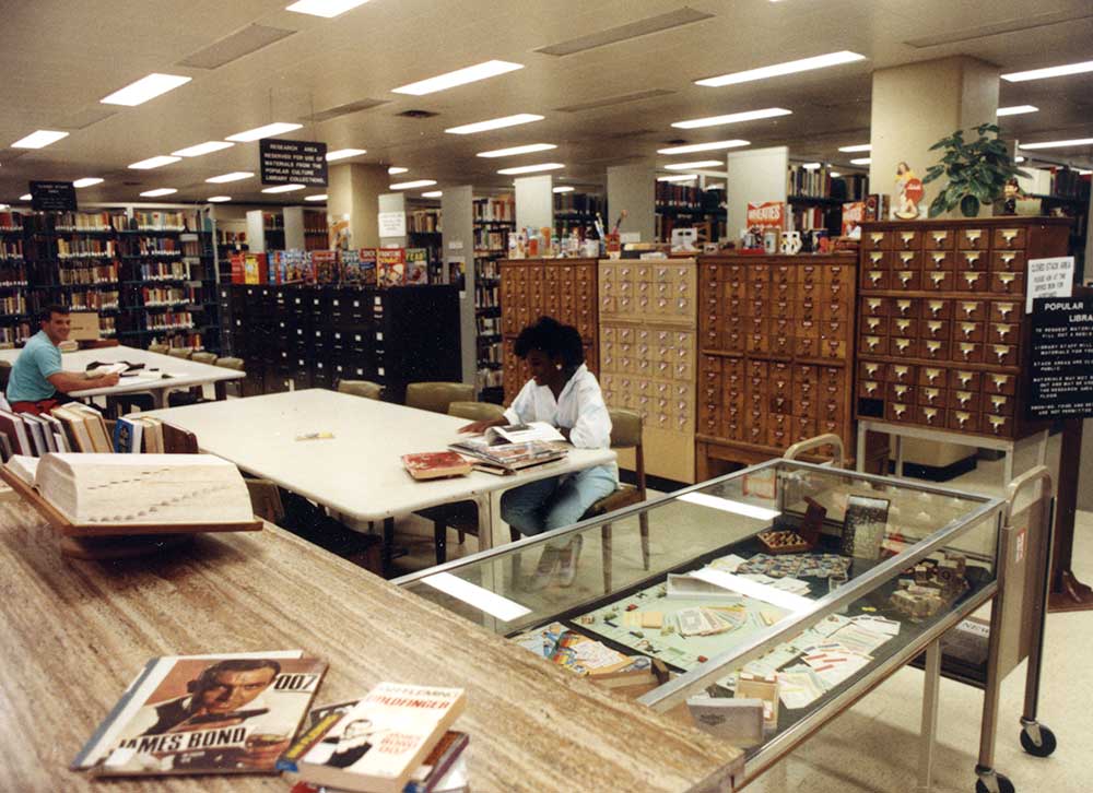 Color photograph of two college students studying at tables in a library