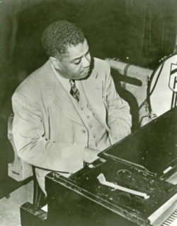 Black and white photo of musician Art Tatum sitting at a piano