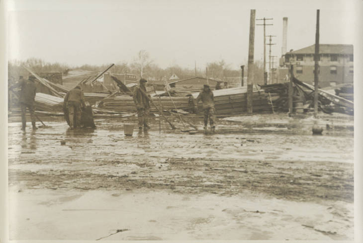 sepia toned image of people working in a flooded street