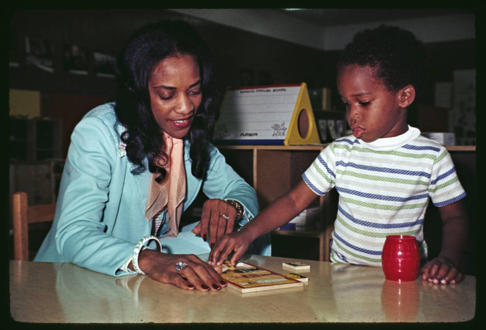 Color photograph of a woman and young boy looking at a puzzle on a table